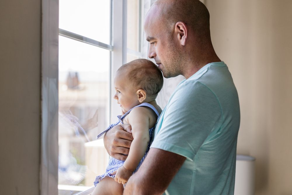 Father with baby looking out window