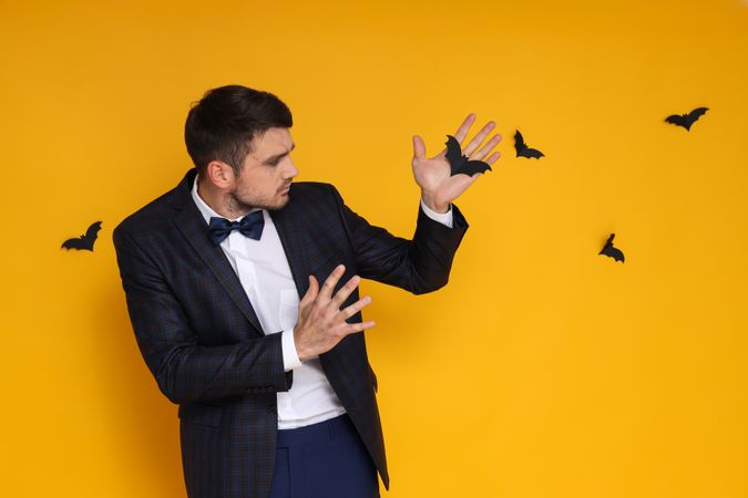 A man in a business suit with zombie makeup on a yellow background