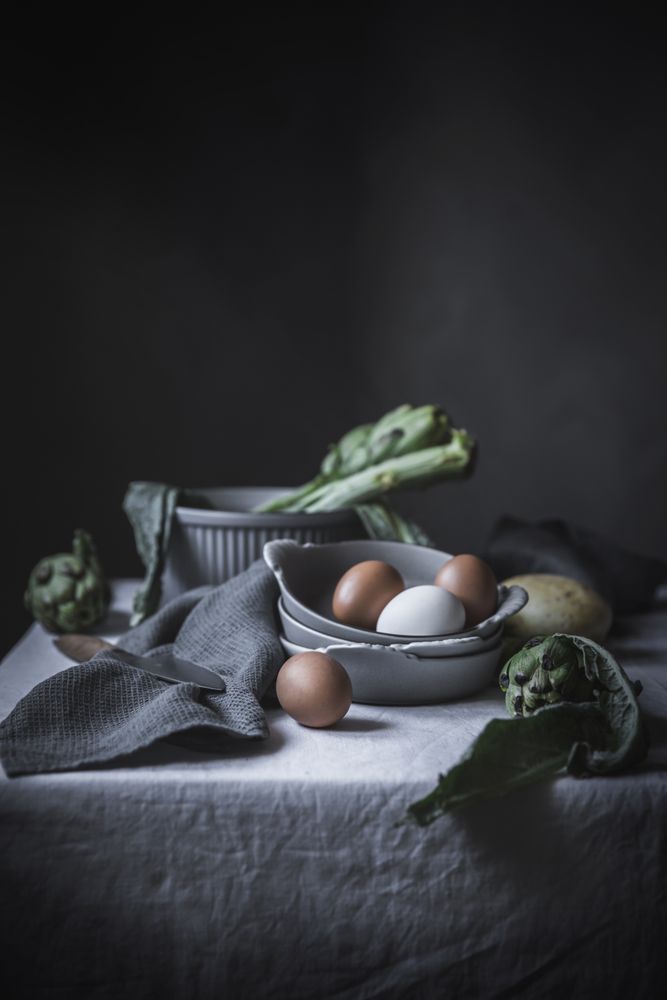 Eggs and different herbs in bowls placed on rustic table