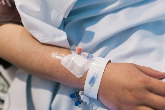 Close up view of the hand of a patient in a hospital bed.