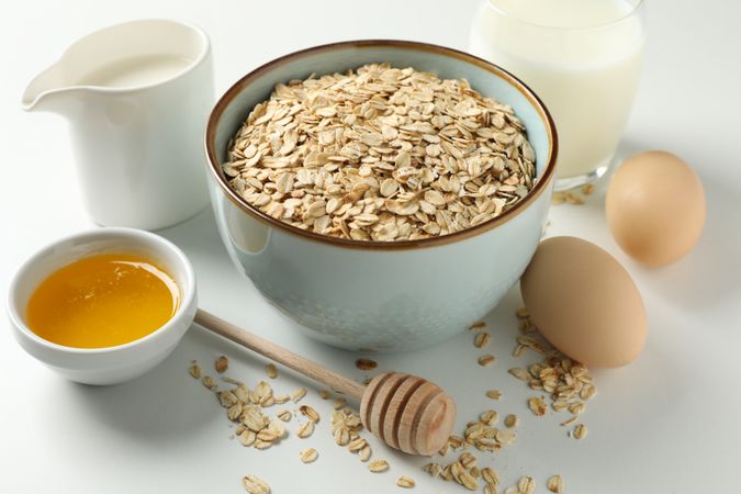 Composition with oatmeal flakes on plain background, close up. Cooking breakfast
