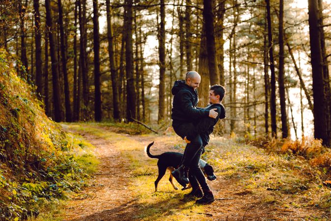 Men hugging and kissing on countryside road near dog