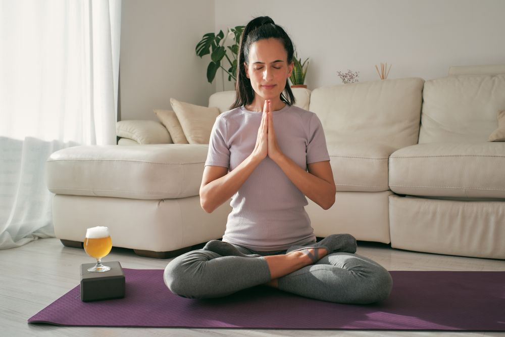 Woman meditating near glass of beer