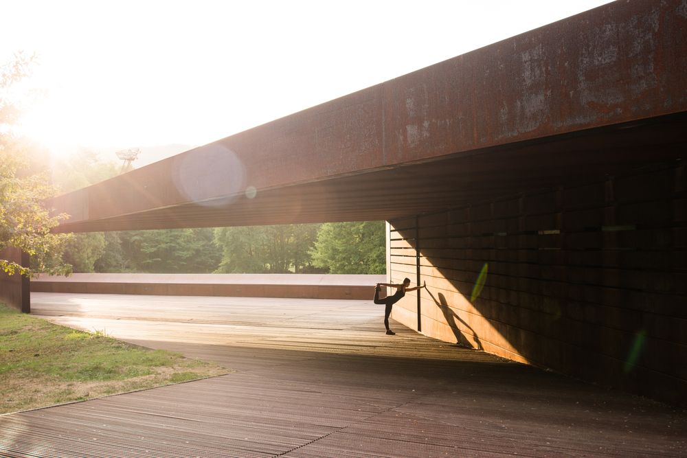 young woman stretching leaning in a amazing geometrical building