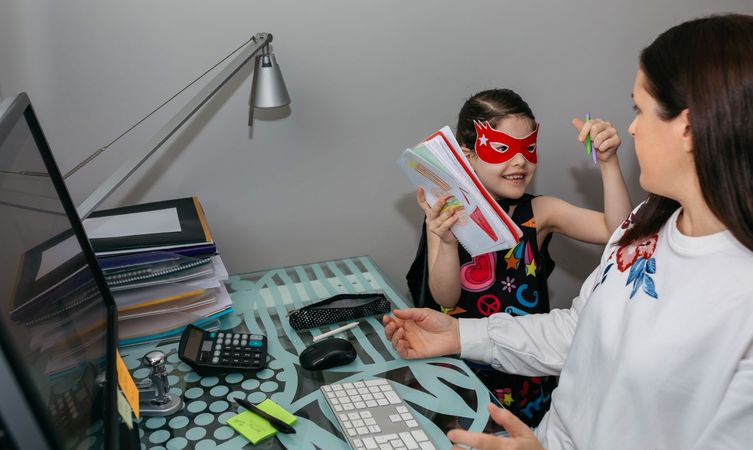 Woman working from home with her daughter interrupting her