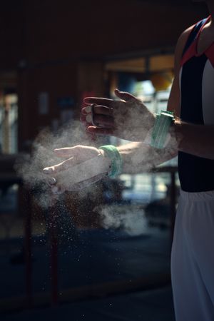 Unrecognizable sportsman preparing himself by putting magnesium in his hands to do the exercises of sport gymnastics.