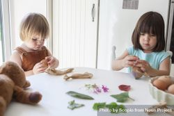 Girl and boy sitting in kitchen decorating eggs 49X1a5