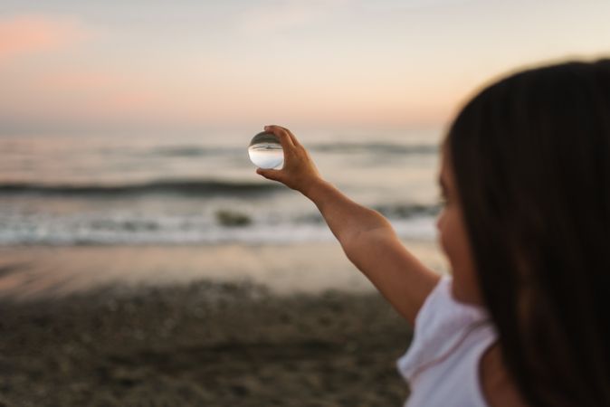 Girl playing with glass ball on seaside