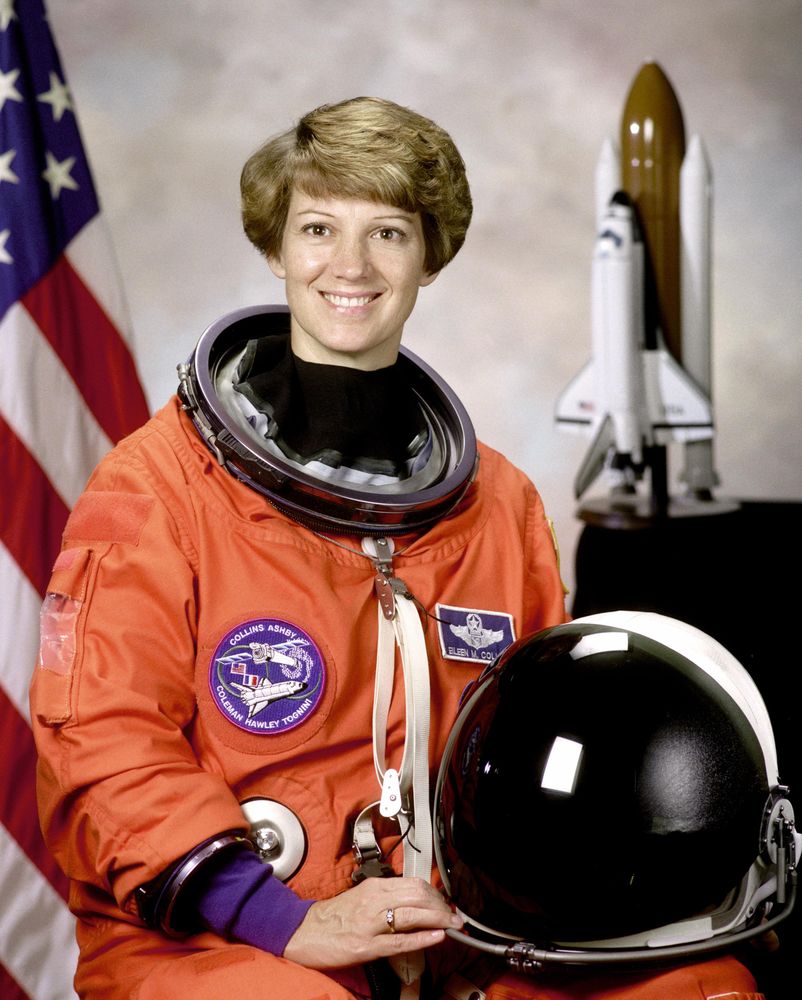 Portrait of Eileen M Collins shown wearing orange Launch and Entry Suit with helmet