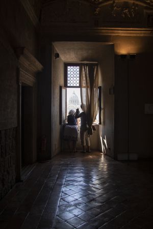 Back view of two people standing at the window in a dark room