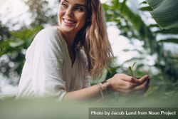 Woman holding small plant and smiling in the garden 4mdGo5