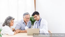 Doctor using computer discussing test result with mature Asian couple 0grmeb