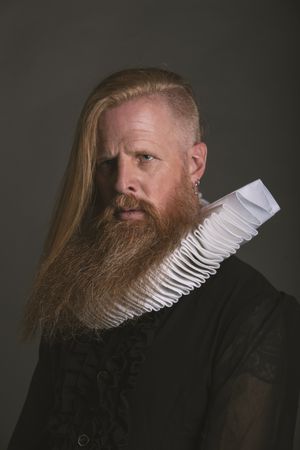 Confident adult red haired medieval magnate looking away