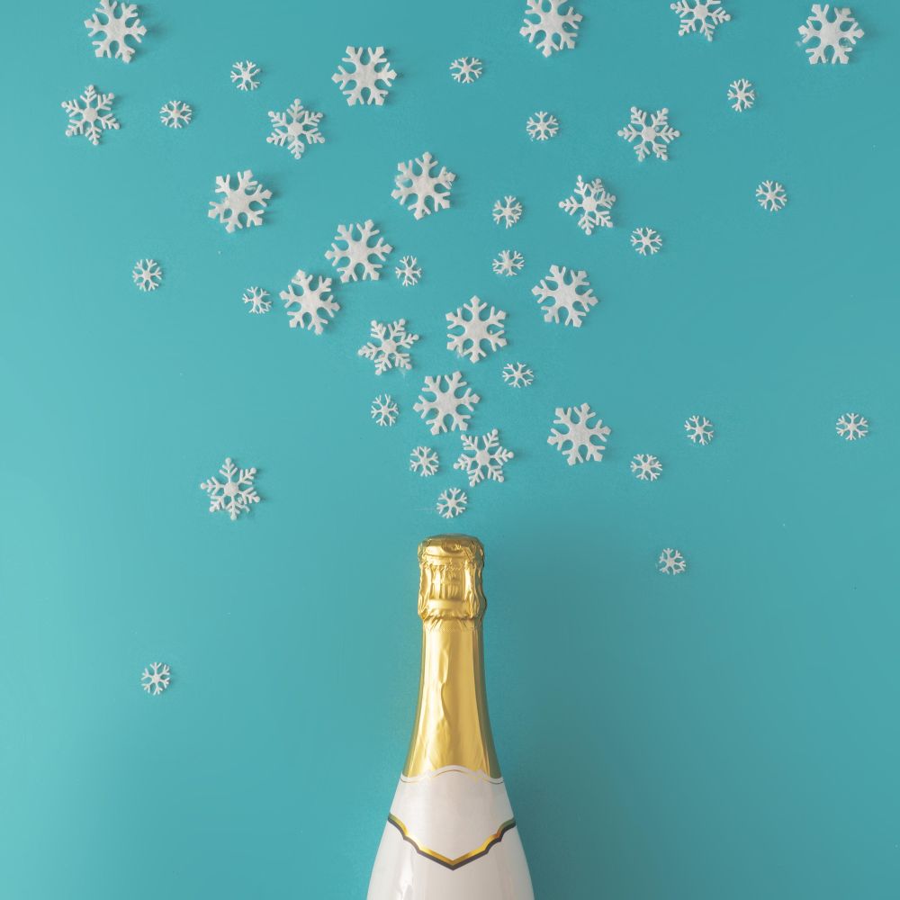Bottle of sparkling wine on blue background with snowflakes