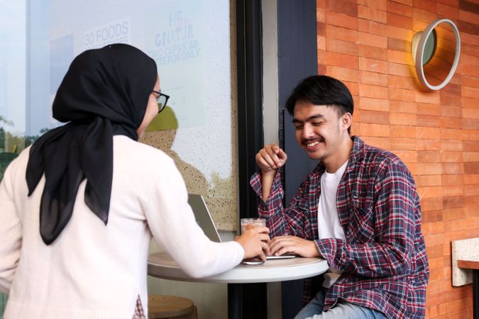 Young Indonesian Asian Smiling to His Woman Friend Who Serving Drink While Working at Cafe Table