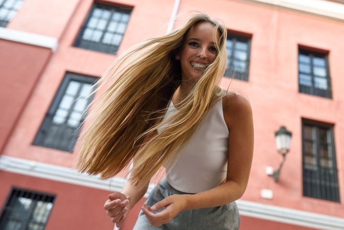 Looking up at joyful blonde woman smiling in the street