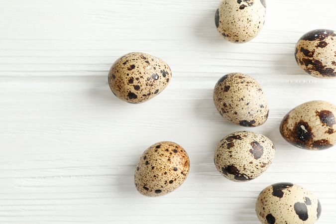 Flat lay composition with quail eggs on wooden background, space for text and closeup