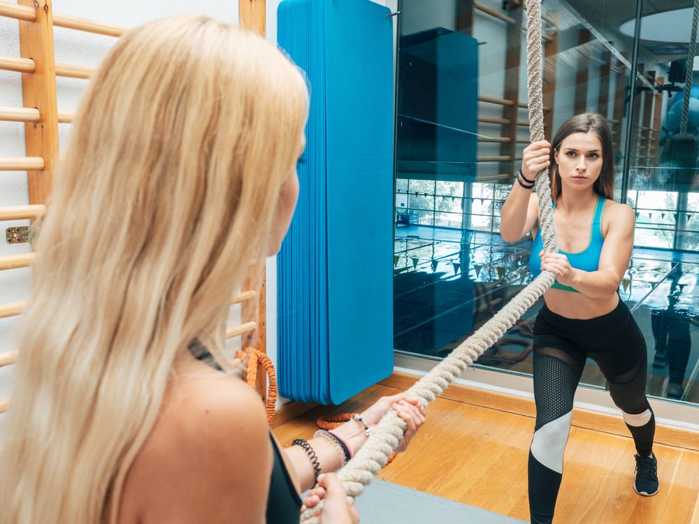 Female athletes training with rope in gym
