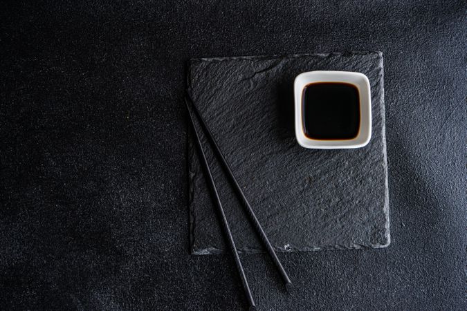 Asian table setting with dark slate, chopsticks and dipping soy sauce