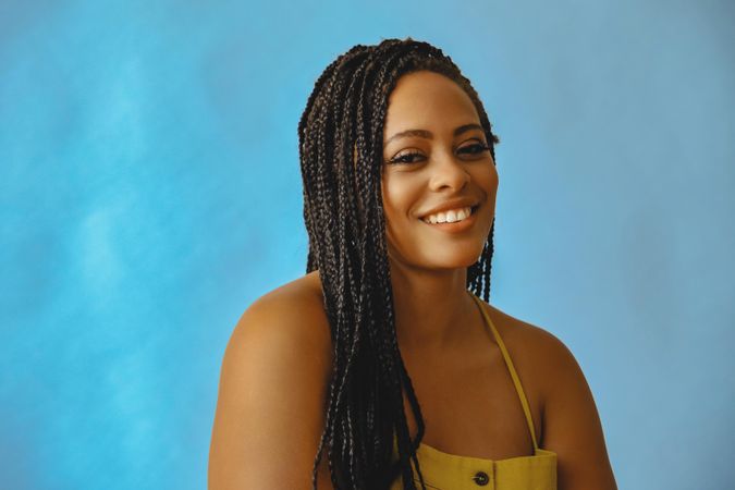 Portrait of happy female with long braided hair in yellow shirt