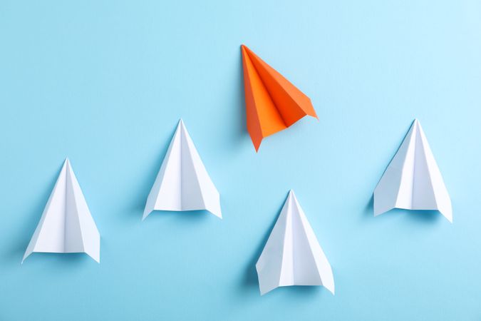 Paper airplanes on blue background, space for text