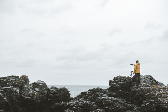 Man standing on rock and taking picture of sea