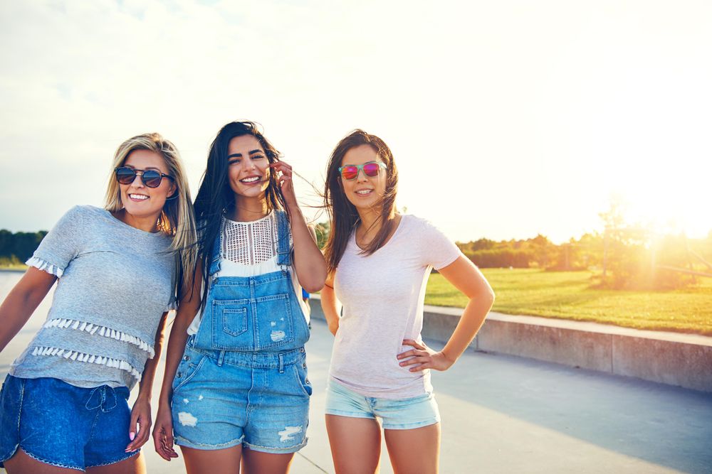 Smiling female friends balancing posing for photo outside, copy space