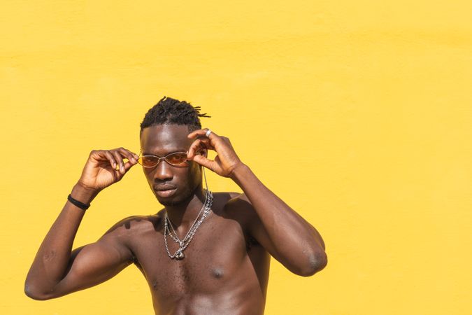 Serious Black man in trendy sunglasses near wall