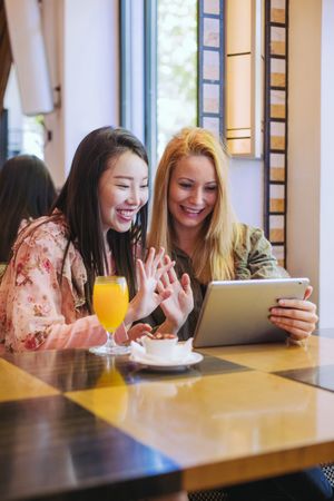 Female friends using tablet in cafe