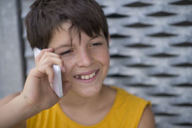 Smiling teenage boy in yellow shirt talking on phone