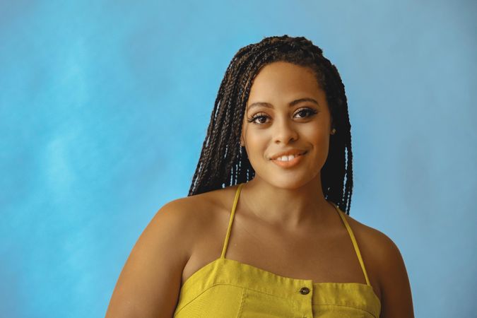 Portrait of smiling female with long braided hair in yellow shirt