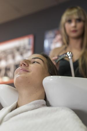Female with head back in sink at hairdressers having her hair washed, vertical