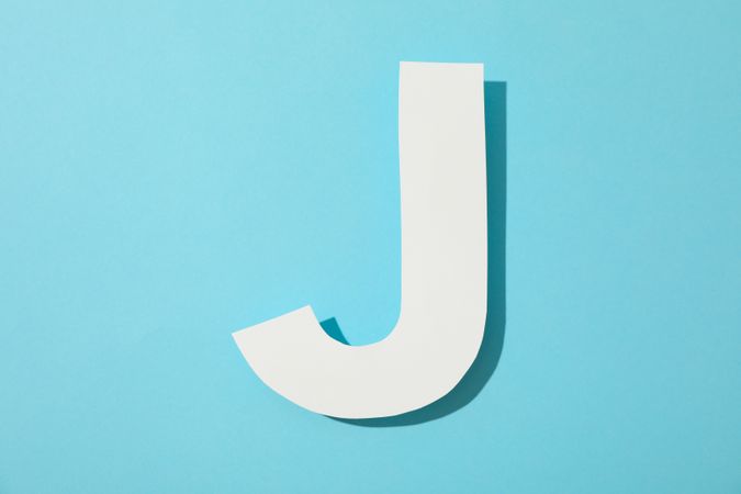 Paper letter J on color background, space for text
