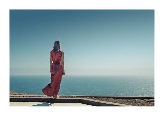 Woman in red dress overlooking the ocean