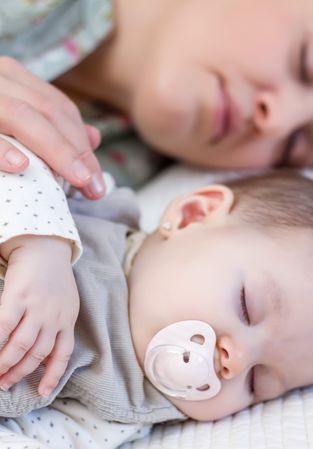 Young mother and her baby girl sleeping in the bed