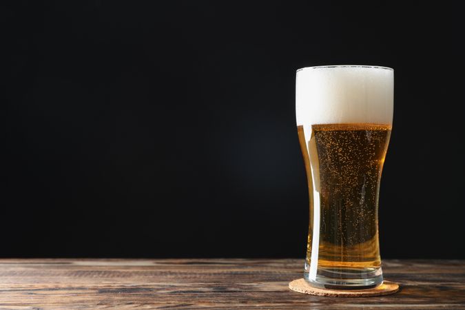 Mug with beer on wooden table, space for text