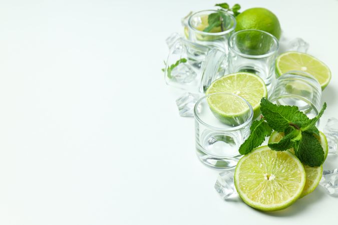 Glasses for shots and ingredients for cocktails on blank background