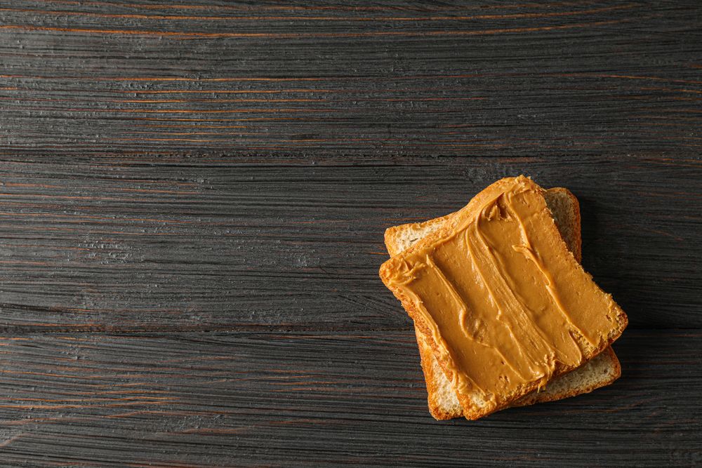 Peanut butter sandwich on wooden background, space for text and top view