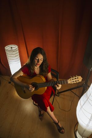 Woman singing and playing guitar on stage in lamplight