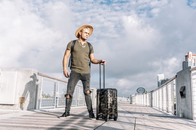 Traveler man with a hat walking with suitcase in the street