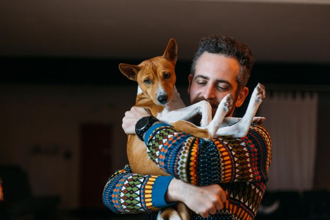 Man in sweater holds dog