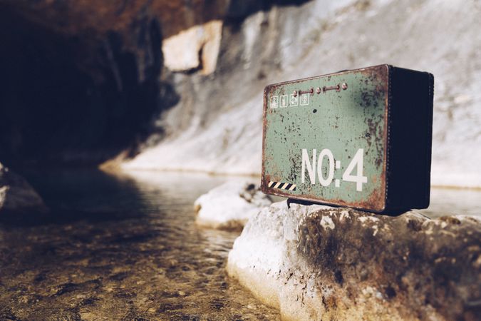 Rusty metal case on rock in lake