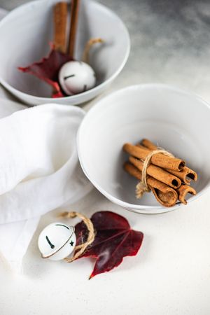 Winter table setting of cinnamon sticks in bowls with bell ornaments and leaf