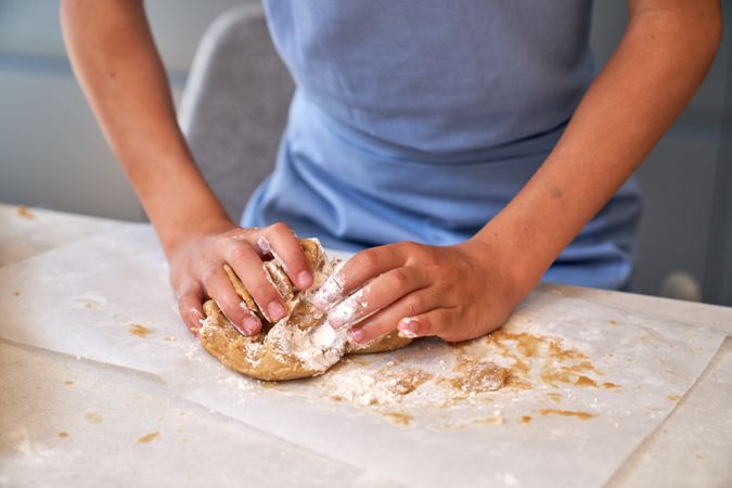 Anonymous kid kneading cookie dough on table