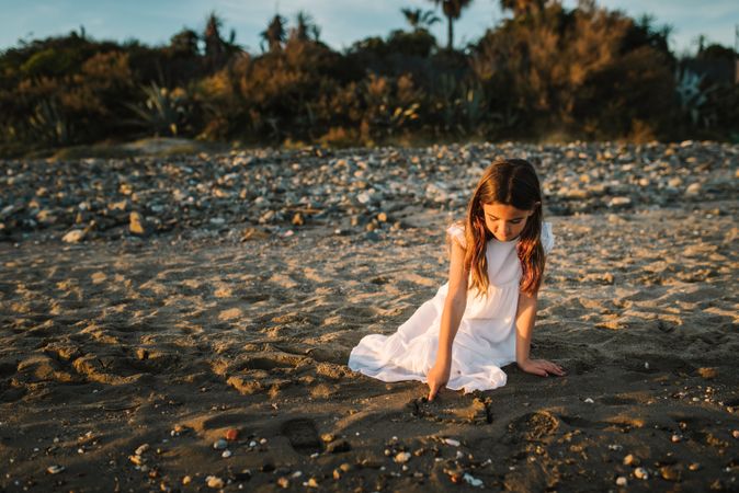 Adorable girl playing with sand on beach
