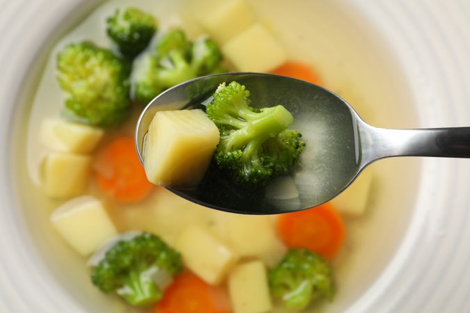 Top view of bowl of vegetable soup with spoon