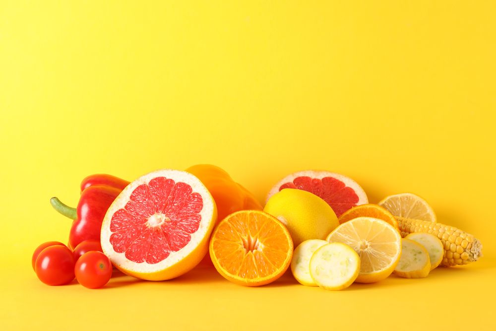 Different vegetables and fruits on yellow background, copy space