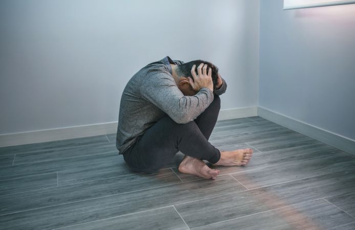 Unrecognizable man with problems sitting on the floor