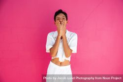 Young gay man smiling with hands over his face standing against pink wall 5pxRN5