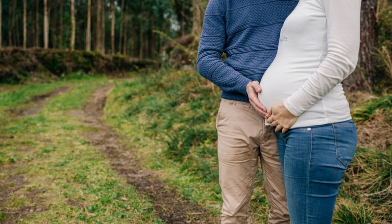 Pregnant woman with partner holding belly